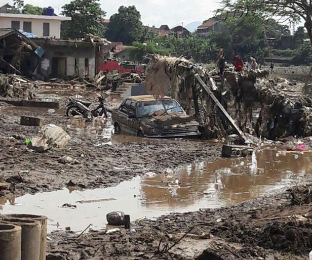 Ein Auto und ein Motorrad sind von Schlamm bedeckt, nachdem ein Hochwasser ein Dorf verwüstet hat.