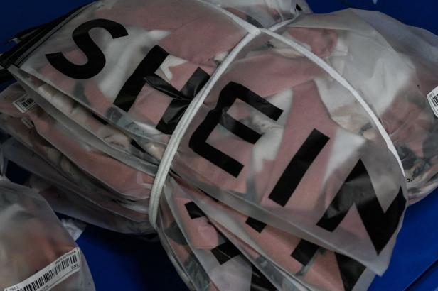 Ein Stapel von Kleidungsstücken der Marke Shein, verpackt in Plastiktüten und mit einem Seil zusammengebunden.