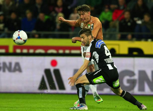 Zwei Fußballspieler kämpfen um den Ball während eines Spiels.