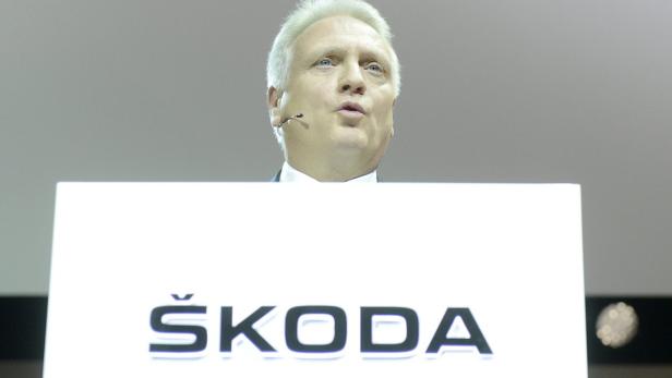 Ein Mann spricht vor einem Podium mit dem Škoda-Logo.