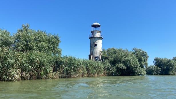 Weißer Leuchtturm in Sulina/Rumänien im Donaudelta, Gebüsche und grünes Wasser rundherum