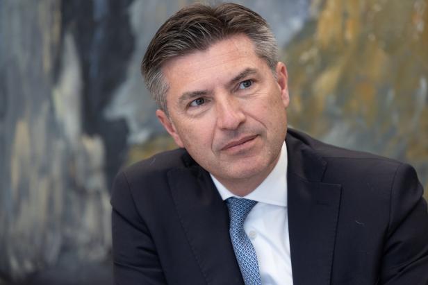 Ein Mann in Anzug und Krawatte blickt nachdenklich zur Seite.