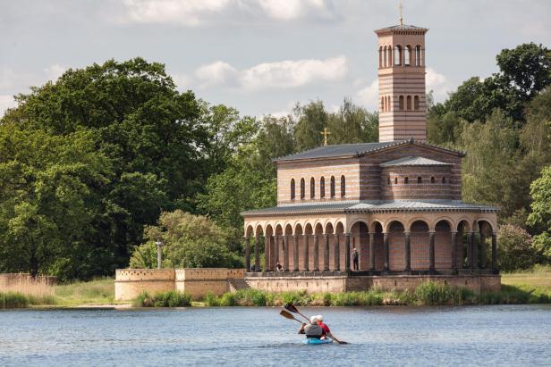 Die Heilandskirche Sacrow in Brandenburg, gesehen vom Wasser aus, mit einem Kanu im Vordergrund.