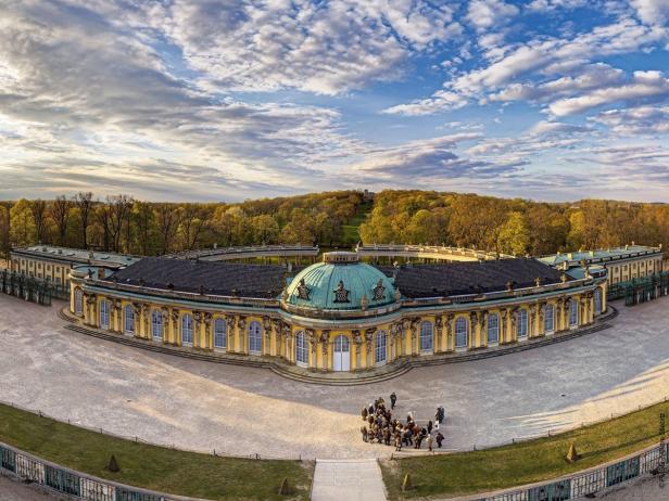 Das Schloss Sanssouci in Potsdam von oben mit Besuchern im Hof.