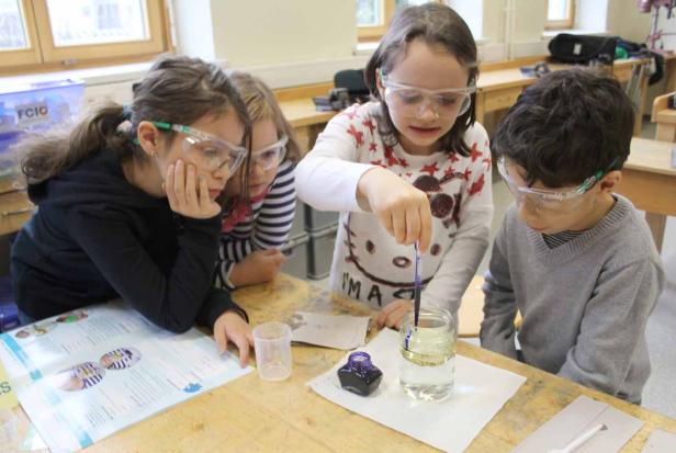Eine Gruppe von Kindern führt ein Experiment mit Flüssigkeiten im Klassenzimmer durch.
