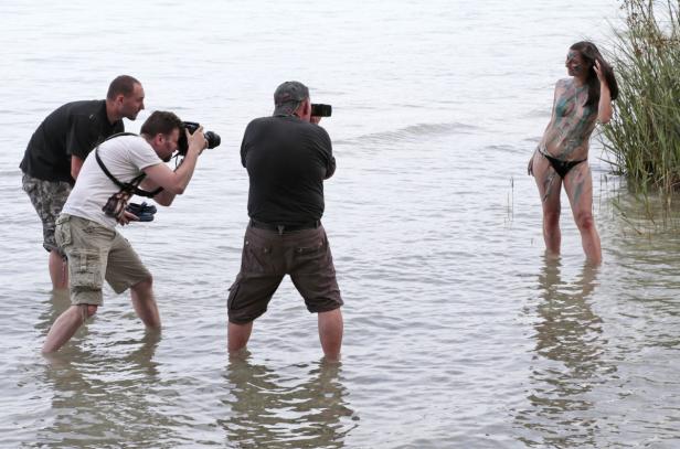 Zwei Fotografen fotografieren eine Frau mit Körperbemalung im Wasser.