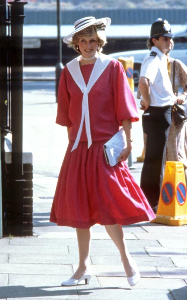 Prinzessin Diana in einem roten Kleid und Hut auf der Straße.