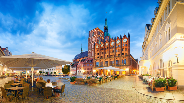Der Alte Markt in Stralsund mit dem Rathaus und Gästen in den Restaurants.