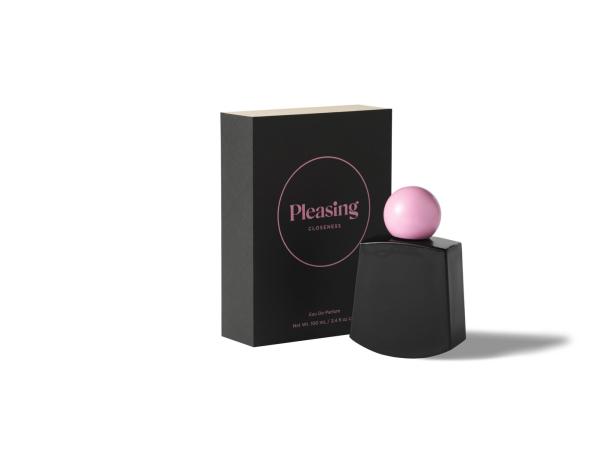 Ein Flakon „Pleasing Closeness“ Eau de Parfum mit rosa Verschlusskugel steht neben der Verpackung.