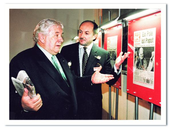 Zwei Männer betrachten eine Ausstellung über die Wahl von Johannes Paul II. zum Papst.