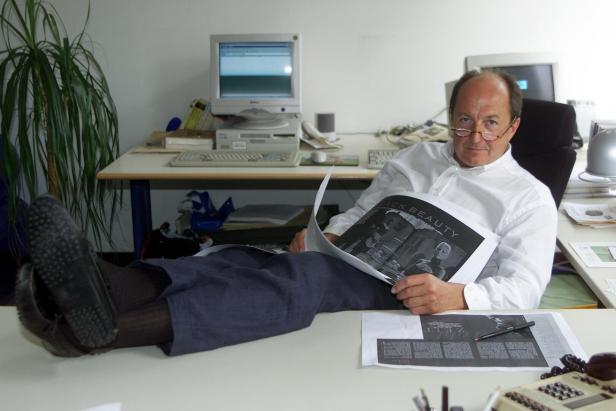 Ein Mann mit Brille liest entspannt eine Zeitung mit dem Titel „Black Beauty“ im Büro.