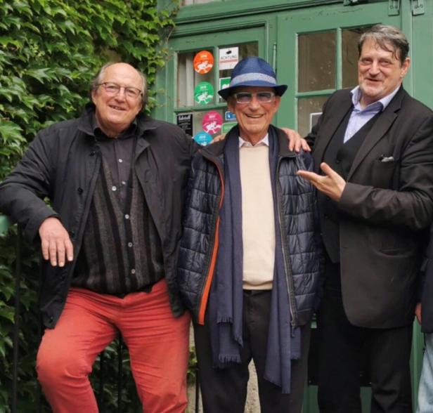 Drei ältere Herren posieren vor einer mit Efeu bewachsenen Tür.