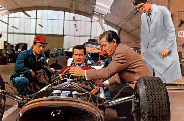 James Garner wird von Mechanikern in einem Rennwagen in „Grand Prix“ umringt.
