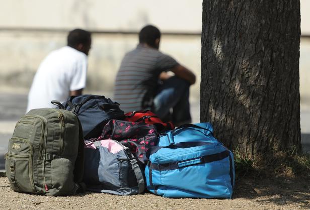 Zwei Männer sitzen hinter einem Berg von Gepäck, man sieht sie nur von hinten.