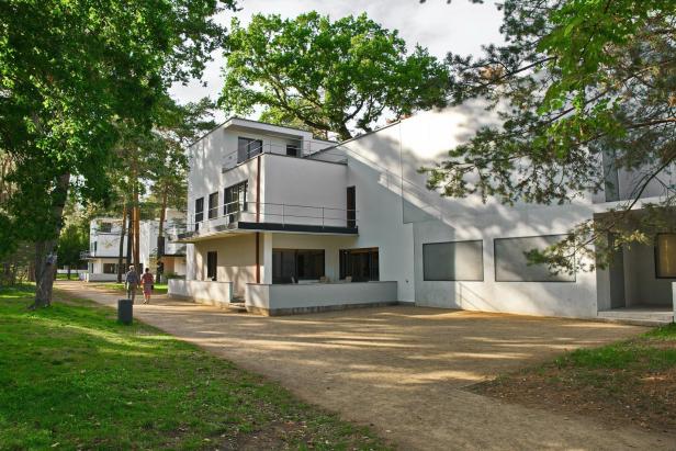 Zwei Personen spazieren auf einem Weg entlang der Bauhaus-Siedlung Dessau-Törten.