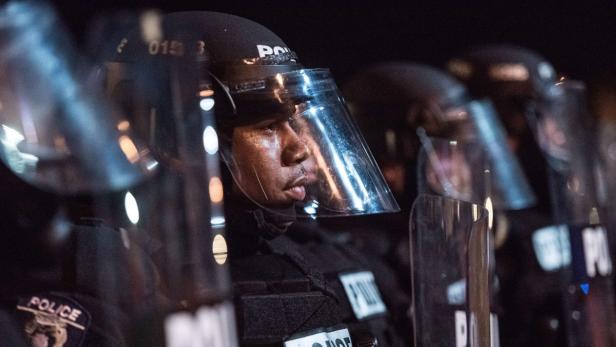 Polizisten stehen in voller Montur mit Schutzschilden in einer Reihe.