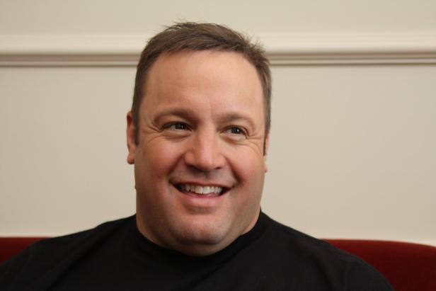 Ein lächelnder Kevin James vor einer hellen Wand.