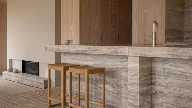 Zwei Holzstühle stehen vor einer Küchentheke aus Travertin.