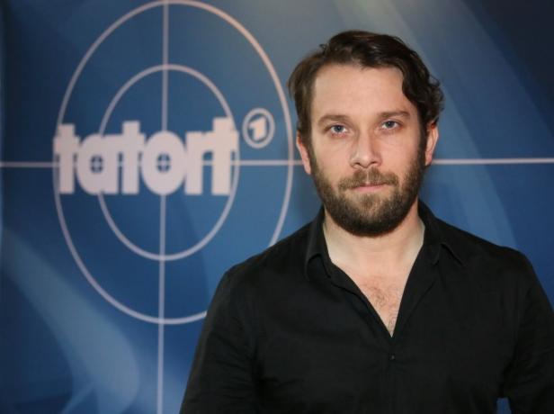 Ein Mann mit Bart posiert vor einem „Tatort“-Logo.