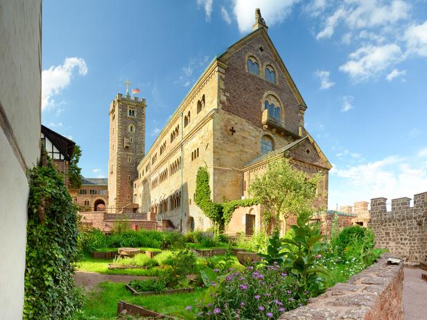 Burg mit Burgmauer und grünem Innenhof.