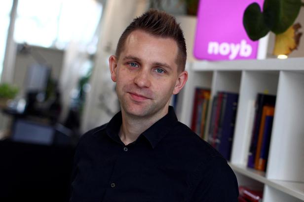 Porträt von Max Schrems vor einem Bücherregal mit dem noyb-Logo.
