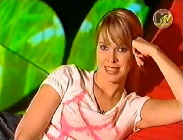 Eine Frau mit blonden Haaren sitzt vor einem MTV-Hintergrund.