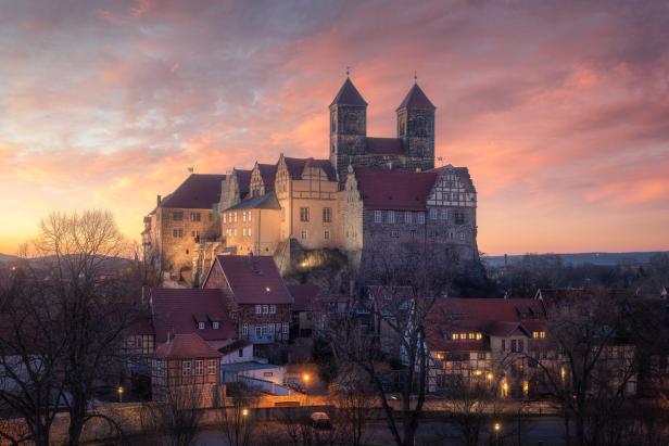 Mittelalterliches Schloss erhebt sich majestätisch auf einem Hügel bei Sonnenuntergang, der Himmel ist rot.