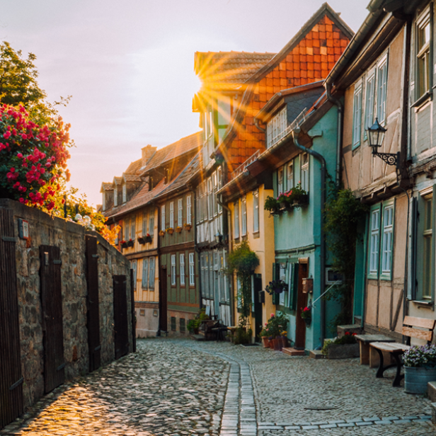 Mittelalterliche Gasse mit Kopfsteinpflaster und bunten Fachwerkhäusern bei Sonnenuntergang.