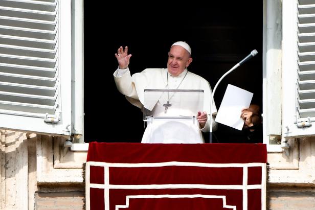 Papst Franziskus winkt von einem Fenster aus.