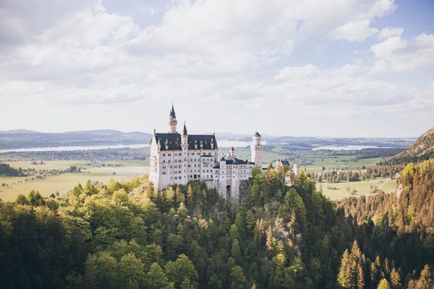 Schloss thront majestätisch auf einem Hügel in malerischer Landschaft.