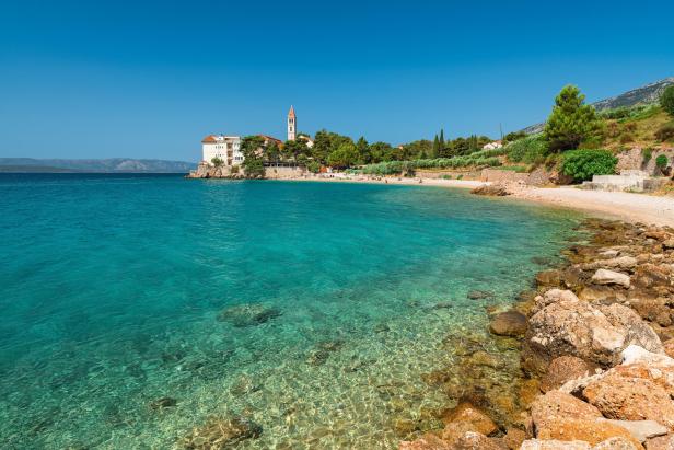 Ein Küstenort mit einem Strand und türkisfarbenem Wasser unter blauem Himmel.