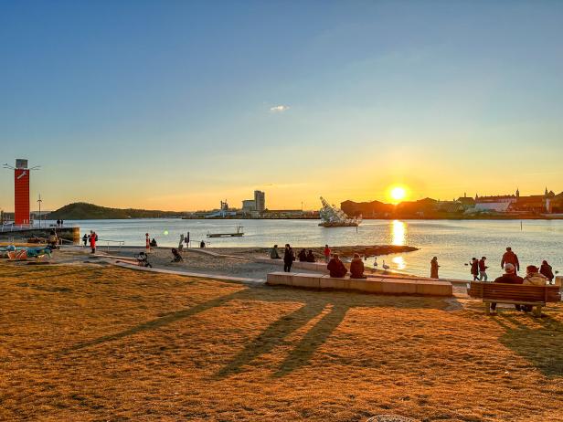 Menschen genießen den Sonnenuntergang am Wasser.