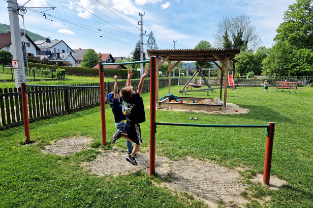 Zwei Jungen spielen auf einem Spielplatz an einer Reckstange.