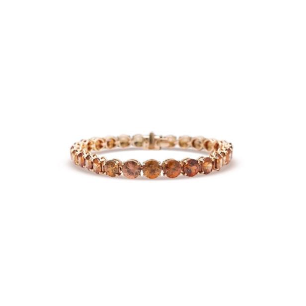Ein goldenes Armband mit orangefarbenen Steinen auf einem weißen Hintergrund.