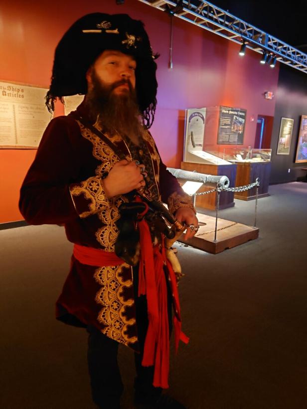 Als Pirat verkleideter Mann im Piratenmuseum in Salem vor Schaukästen