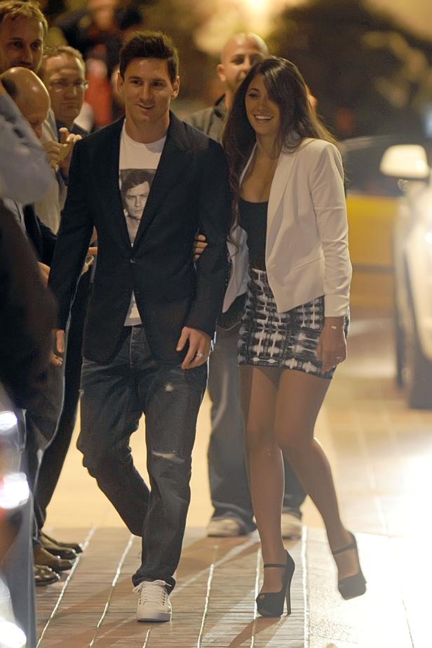 Lionel Messi und seine Frau Antonela Roccuzzo verlassen ein Restaurant, umgeben von Menschen.