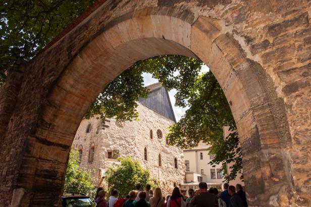 Die Alte Synagoge in Erfurt, gesehen durch einen steinernen Torbogen.