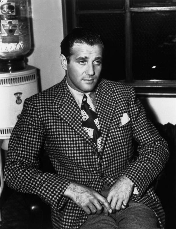 Benjamin „Bugsy“ Siegel sitzt in einem karierten Anzug.