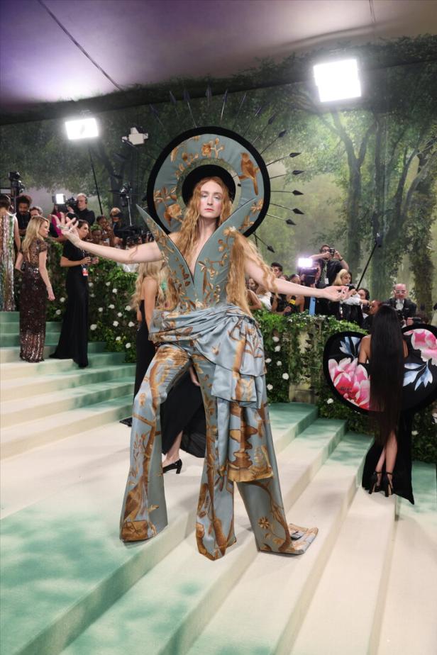 Florence Welch in einem extravaganten, himmelblauen Hosenanzug mit Vogelmotiven auf dem roten Teppich.