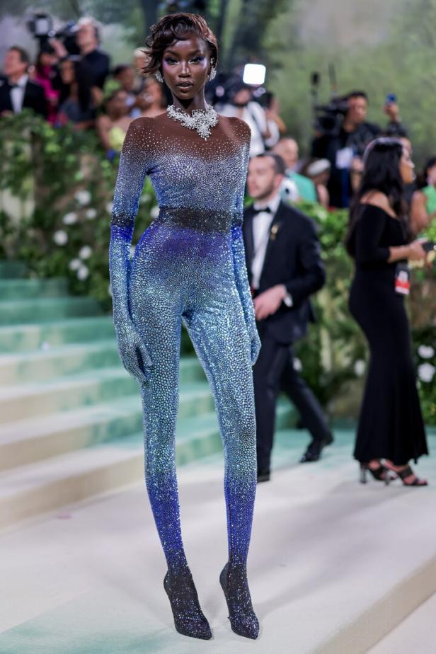 Ein Model präsentiert ein blaues, glitzerndes Pailletten-Ensemble mit passenden Schuhen auf dem Laufsteg.
