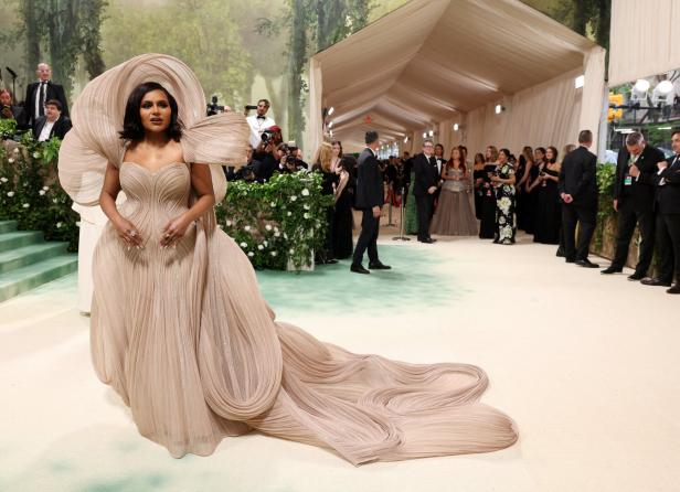 Mindy Kaling in einem beigefarbenen Kleid mit Hut auf dem roten Teppich der Met Gala.