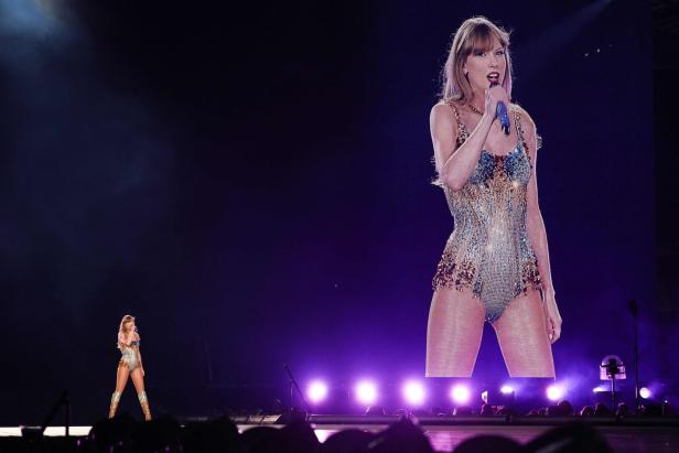 Taylor Swift tritt in einem glitzernden Bühnenoutfit auf einer Konzertbühne auf.