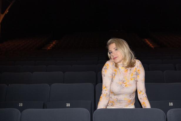 Eine Frau sitzt in einem leeren Theatersaal.