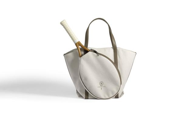 Ein Tennisschläger steckt in einer beigen Segeltuchtasche mit braunen Ledergriffen.