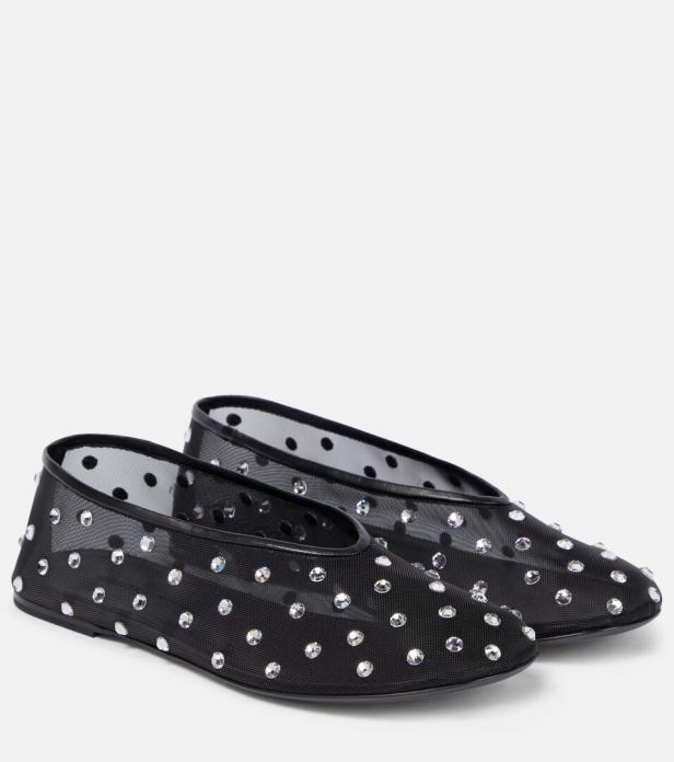 Zwei schwarze, mit Strasssteinen besetzte Ballerinas mit Punktmuster stehen nebeneinander.