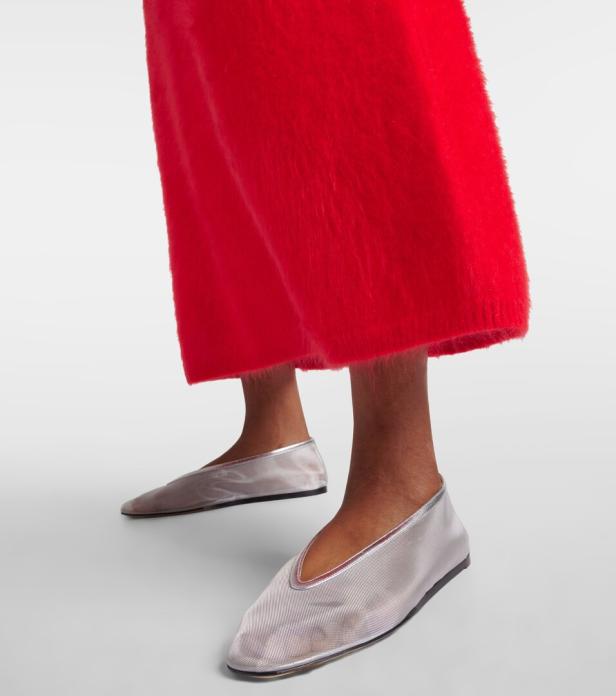 Nahaufnahme von Füßen in silbernen Ballerinas und einer roten Hose.