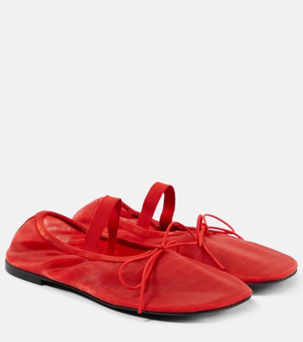 Ein Paar rote Ballerinas mit Schleifen und Riemchen stehen auf einem weißen Hintergrund.