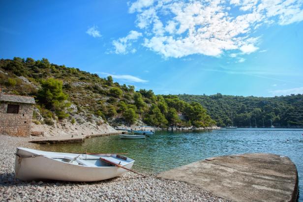 Ein kleines Boot liegt an einem Kiesstrand in einer ruhigen Bucht.