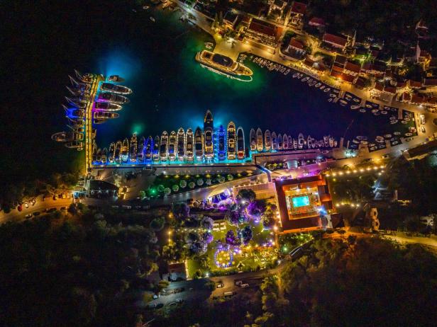 Nachts beleuchtete Küstenstadt mit Yachthafen und einem Resort mit Pool.