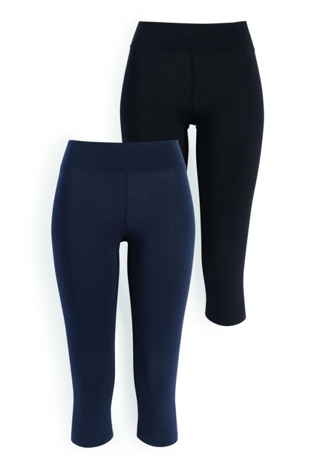 Zwei Capri-Leggings, eine marineblaue und eine schwarze, liegen auf einem weißen Hintergrund.